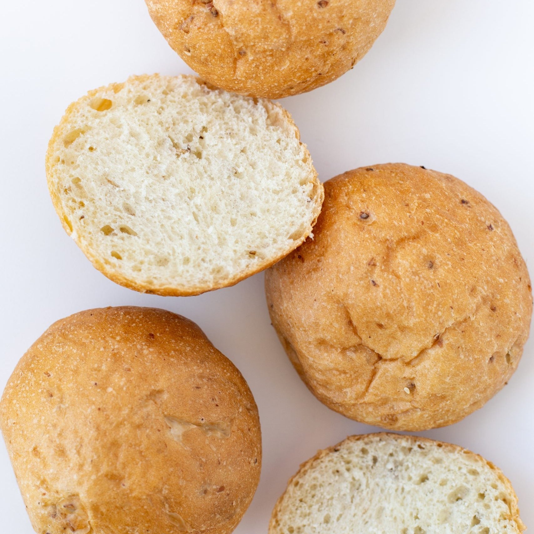 Bread rolls with one cut open on a white background