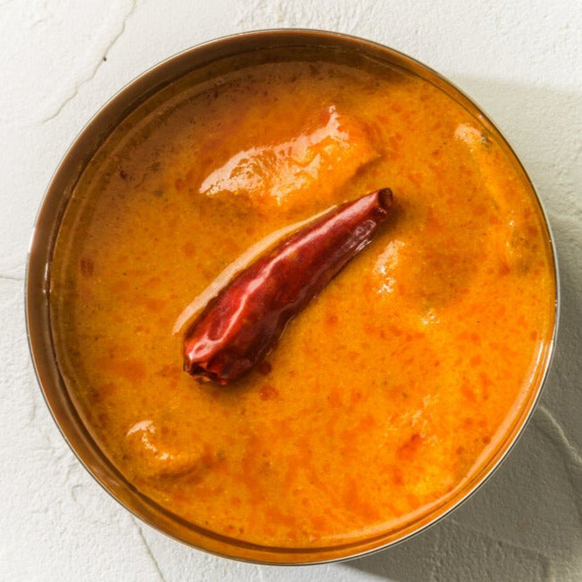 Bowl of Magic Oven's Butter Chicken Sauce with a chili pepper.