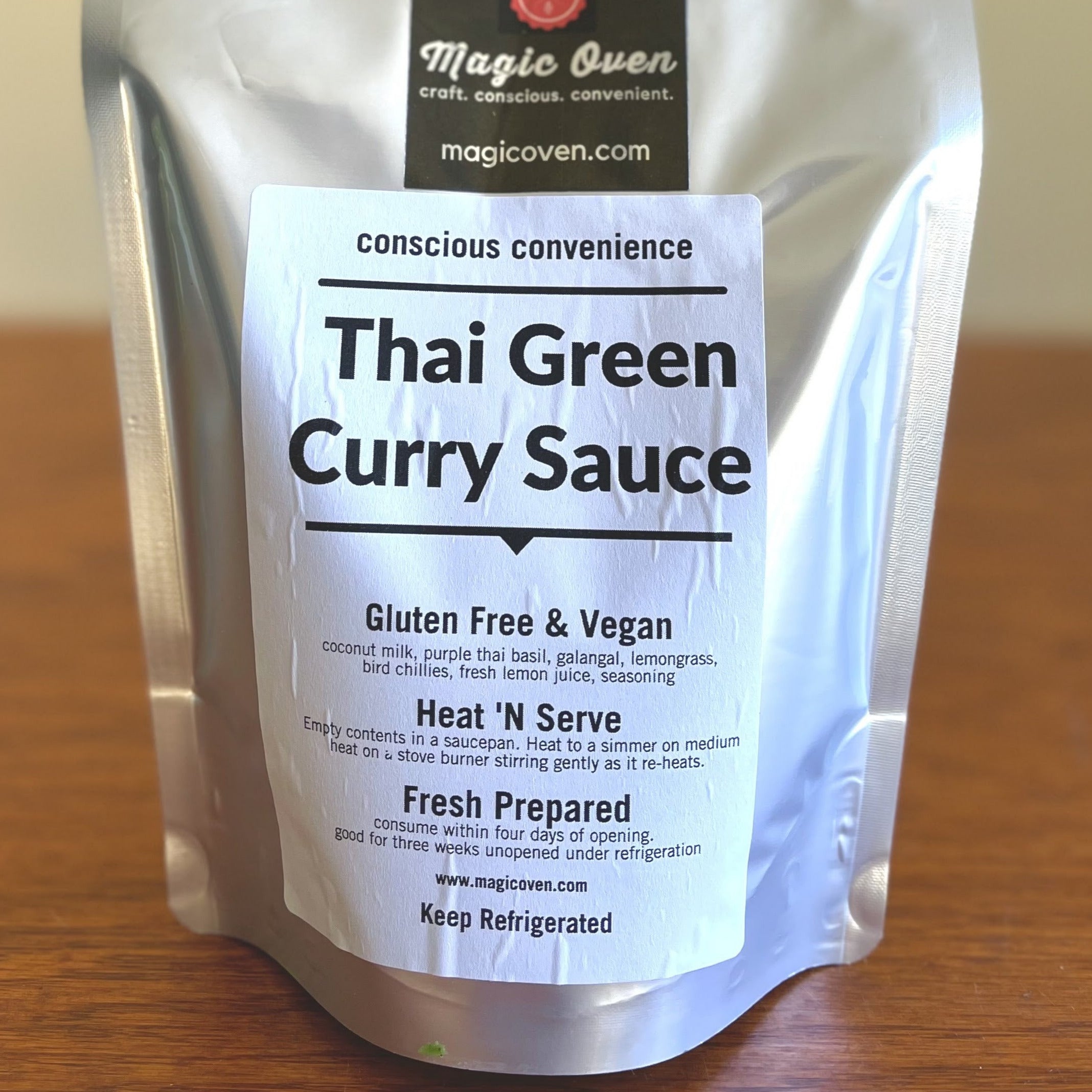 Pouch of Thai Green Curry Sauce. Text: Conscious convenience. Thai Green Curry Sauce. Gluten Free & Vegan: coconut milk, purple thai basiL, galangal, lemongrass, bird chillies, fresh lemon juice, seasoning. Heat 'N Serve: Empty contents in a saucepan. Heat to a simmer on medium heat on a stove burner stirring gently as it re-heats. Fresh Prepared: consume within four days of opening. Good for three weeks unopened under refrigeration. www.magicoven.com. Keep Refrigerated
