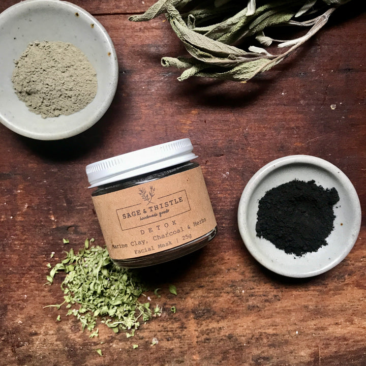 jar of detox facial mask with bowls of powders and dried herbs