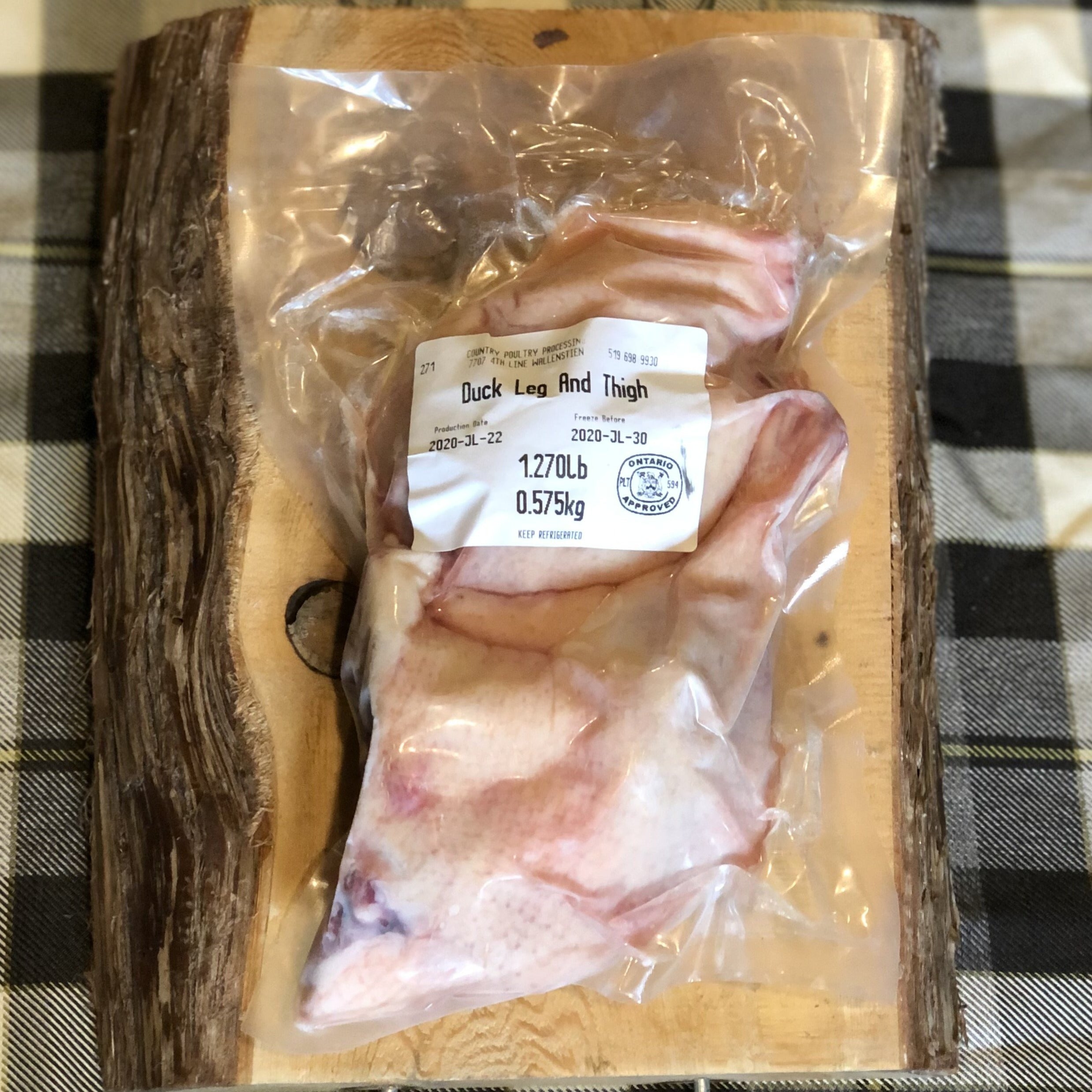 Package of duck legs on a piece of wood